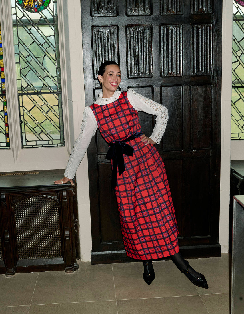 Woman in a red plaid dress standing in front of a stained glass window