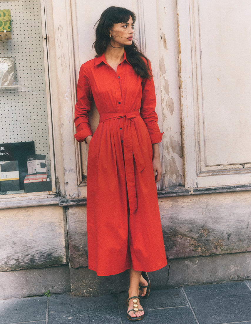 Woman wearing a red dress standing in front of a store window.