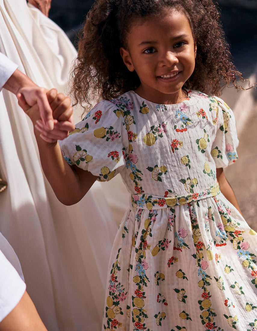 Young girl in a floral dress standing outdoors with a blurred background