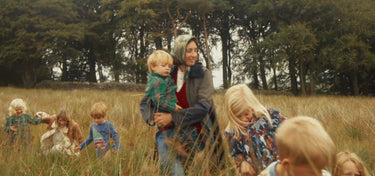 Woman with children in a field with trees in the background