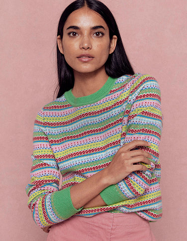 Woman wearing a colorful patterned sweater against a pink background