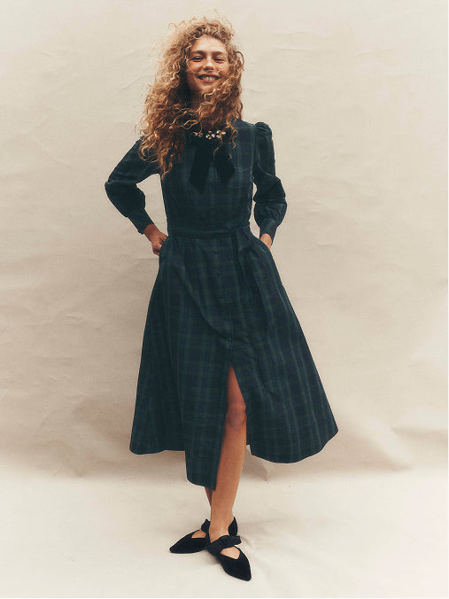 A woman wearing a blue check dress with a white background