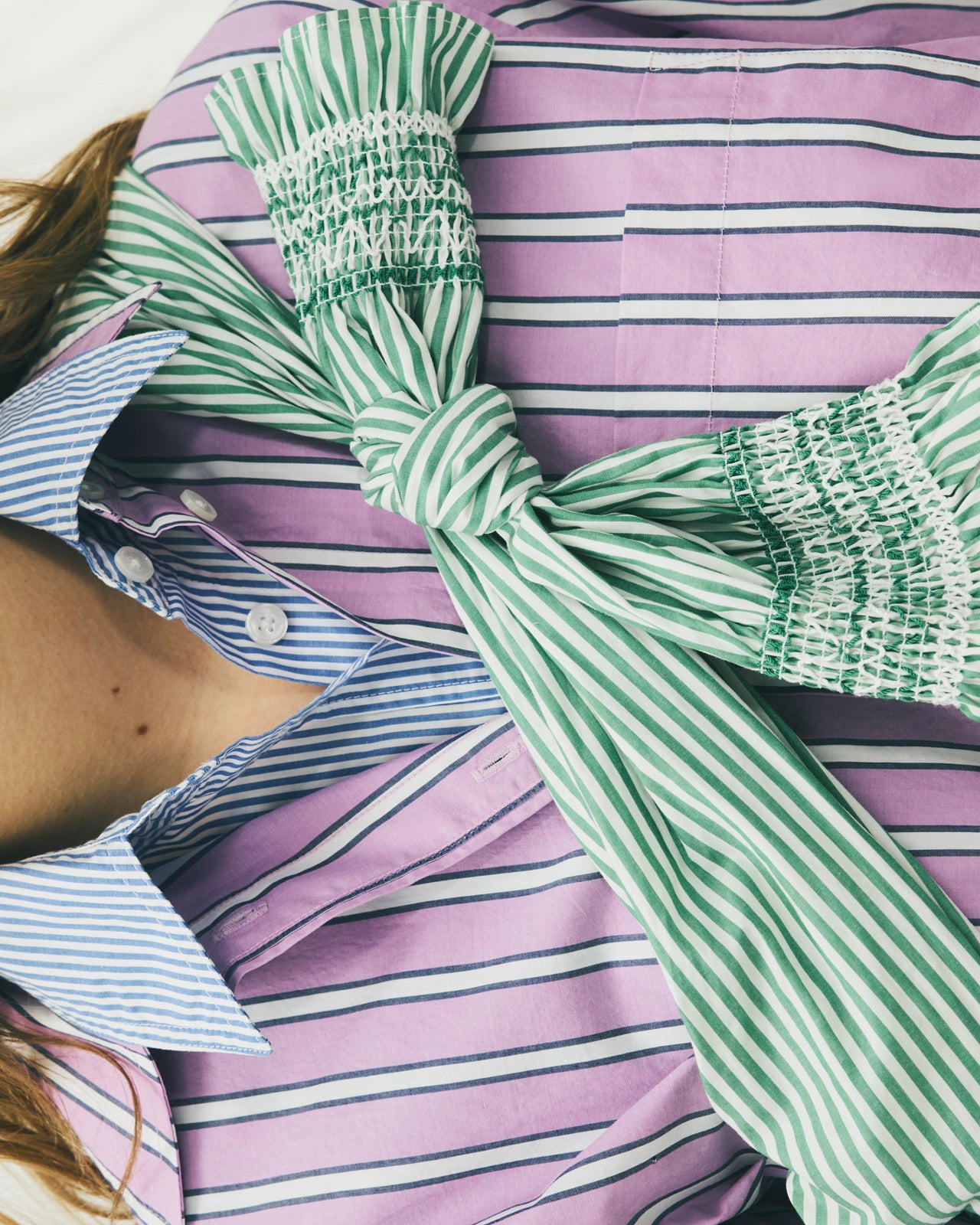 Purple and white striped shirt with green and white striped tie over shoulder