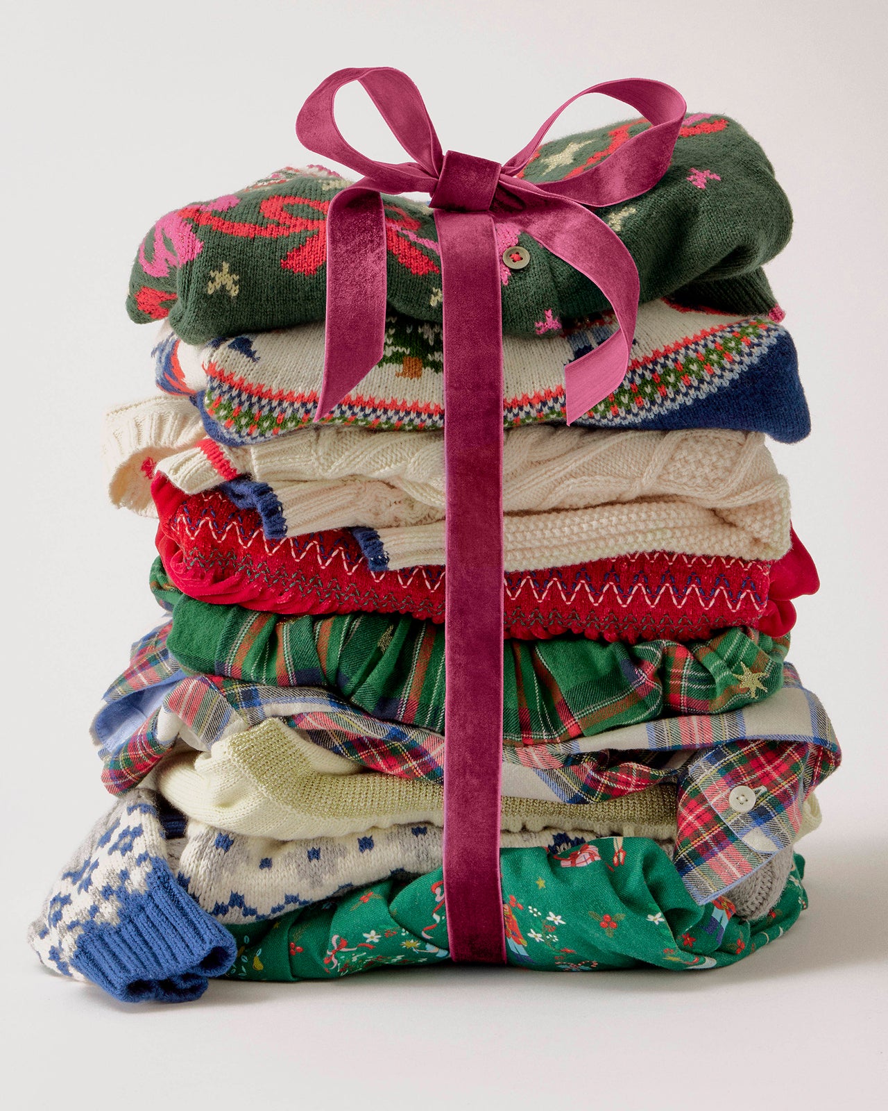 Stack of colorful folded clothes tied with a pink ribbon on a white background