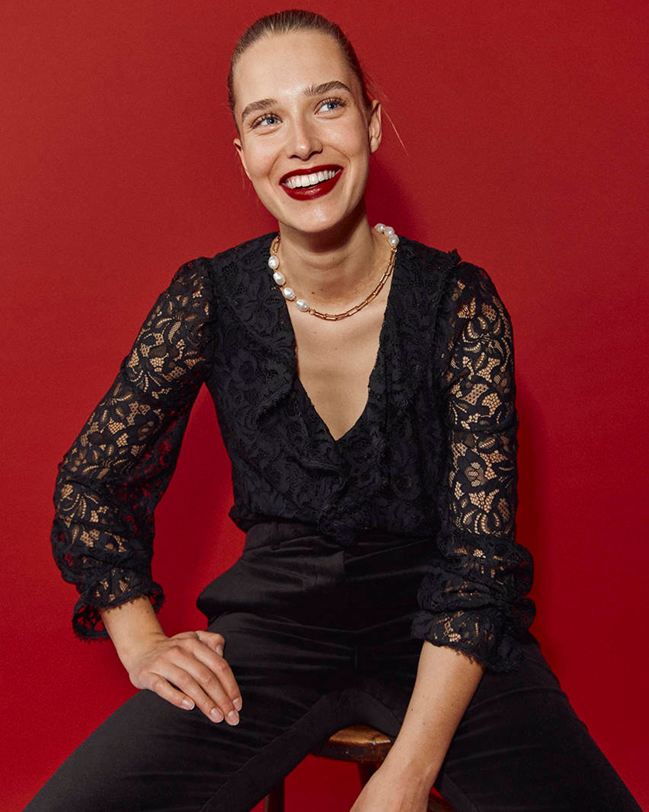 Woman wearing a black lace outfit against a red background