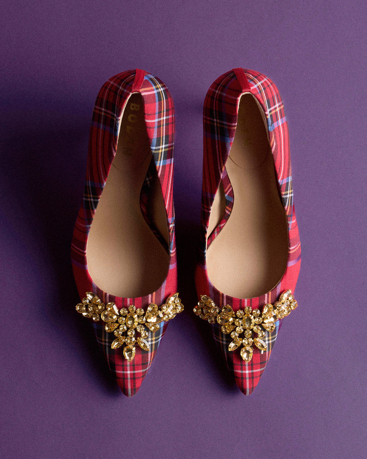 Red tartan pointed flats with gold crystal embellishments on a purple background