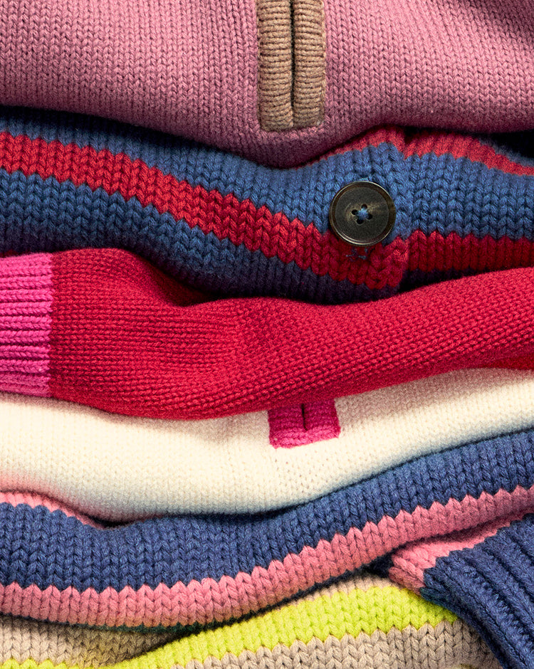 Stack of colorful knit sweaters with a button detail.