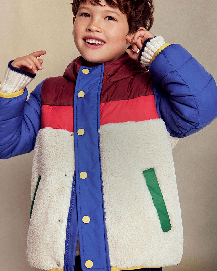 Child wearing a colorful jacket with a neutral background
