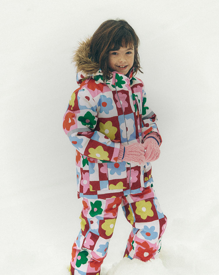 Child wearing a colorful floral-patterned snowsuit on a white background