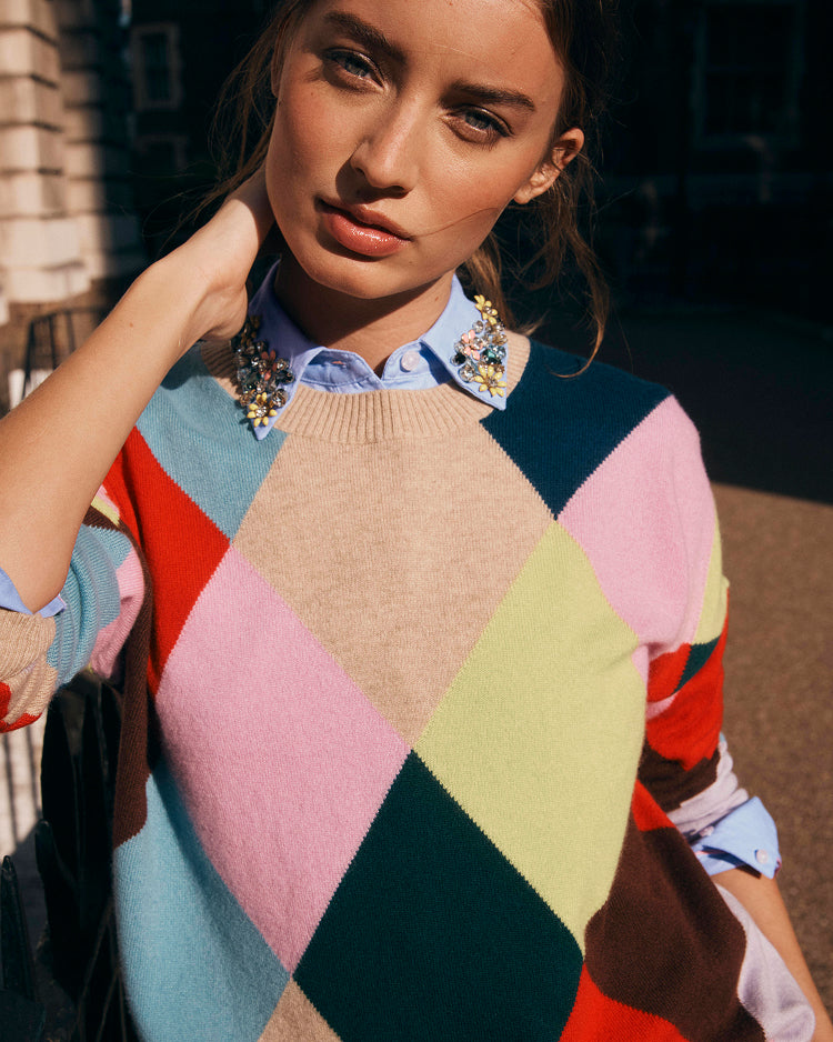 Woman wearing a colorful diamond pattern sweater with a blurred background