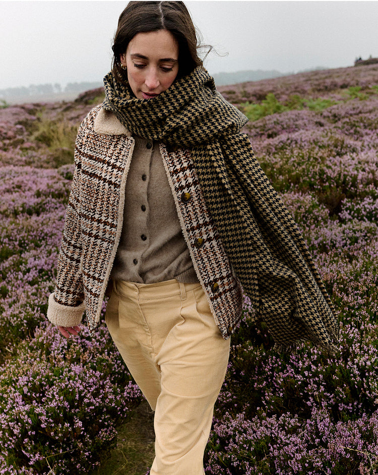 Person wearing a patterned scarf in a field of purple flowers
