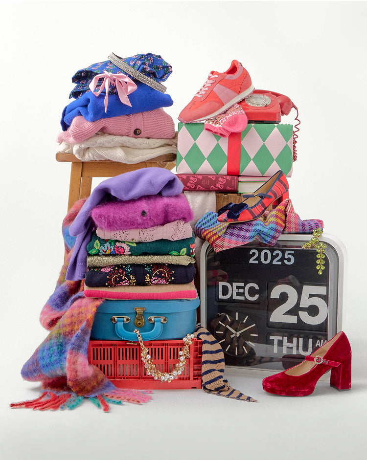 Stack of colorful clothing, shoes, and accessories with a calendar showing December 25th on a white background.