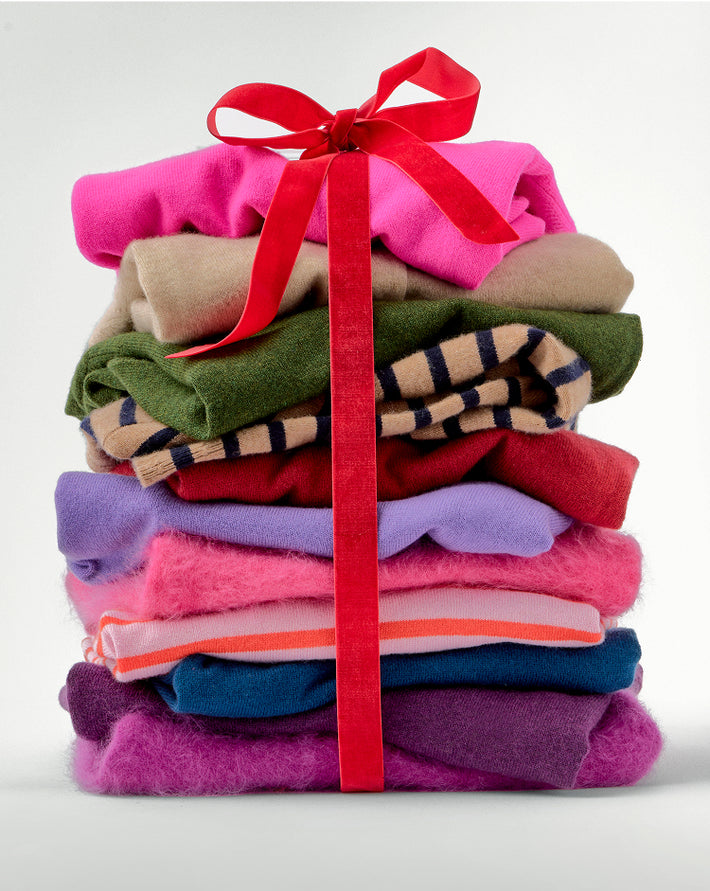 Stack of colorful folded clothes tied with a red ribbon on a white background