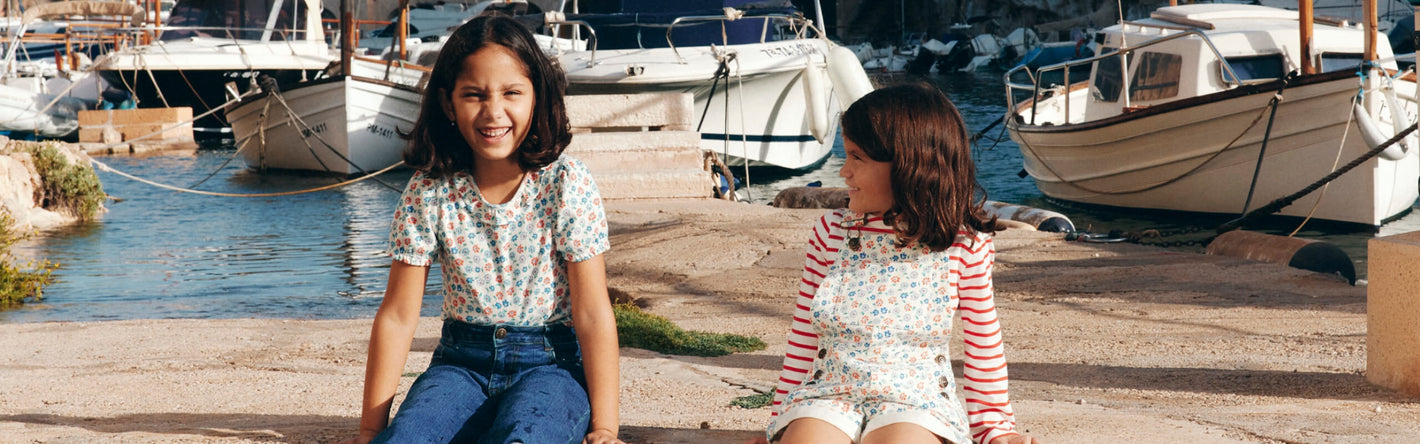 Two girls siting on a dock.