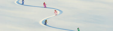 Children skiing on a snowy slope with a blue path.