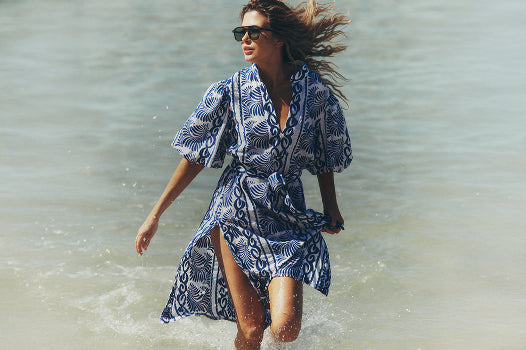 Woman in a blue patterned dress walking on a beach