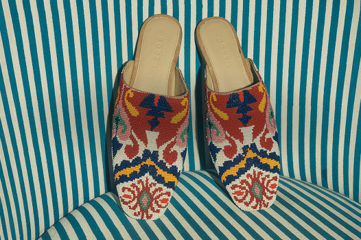 Pair of colorful patterned slippers on a striped cushion