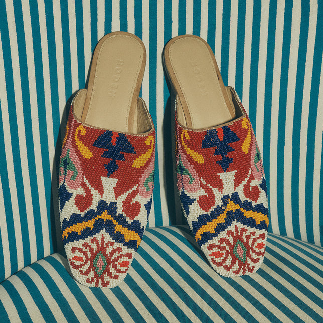 Pair of colorful beaded slippers on a striped chair