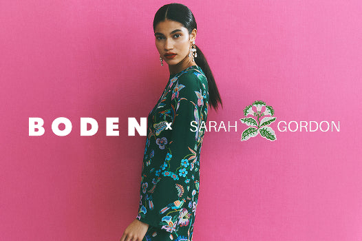 Woman wearing a floral dress against a pink background with 'Boden x Sarah Gordon' branding.