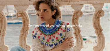 Woman wearing a colorful embroidered sweater by a waterfront with text overlay.