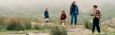 Four people walking on a rocky path with a scenic landscape in the background