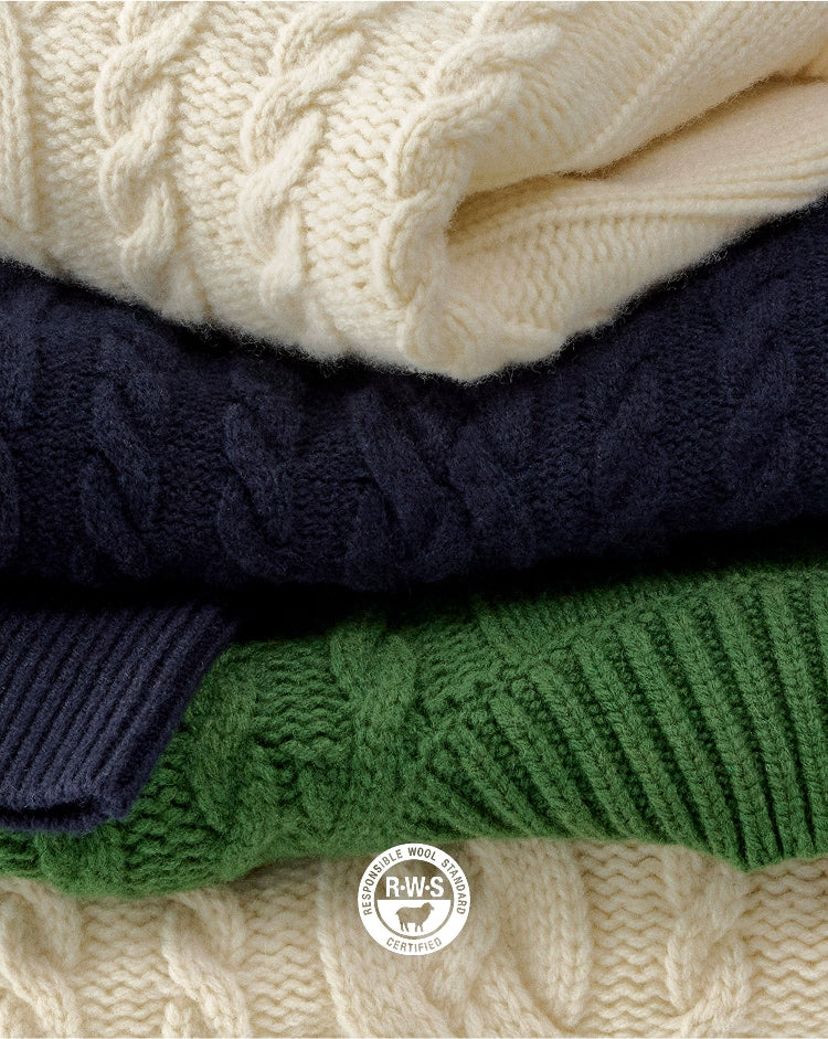 Stack of cable knit sweaters in various colors with a visible brand logo.