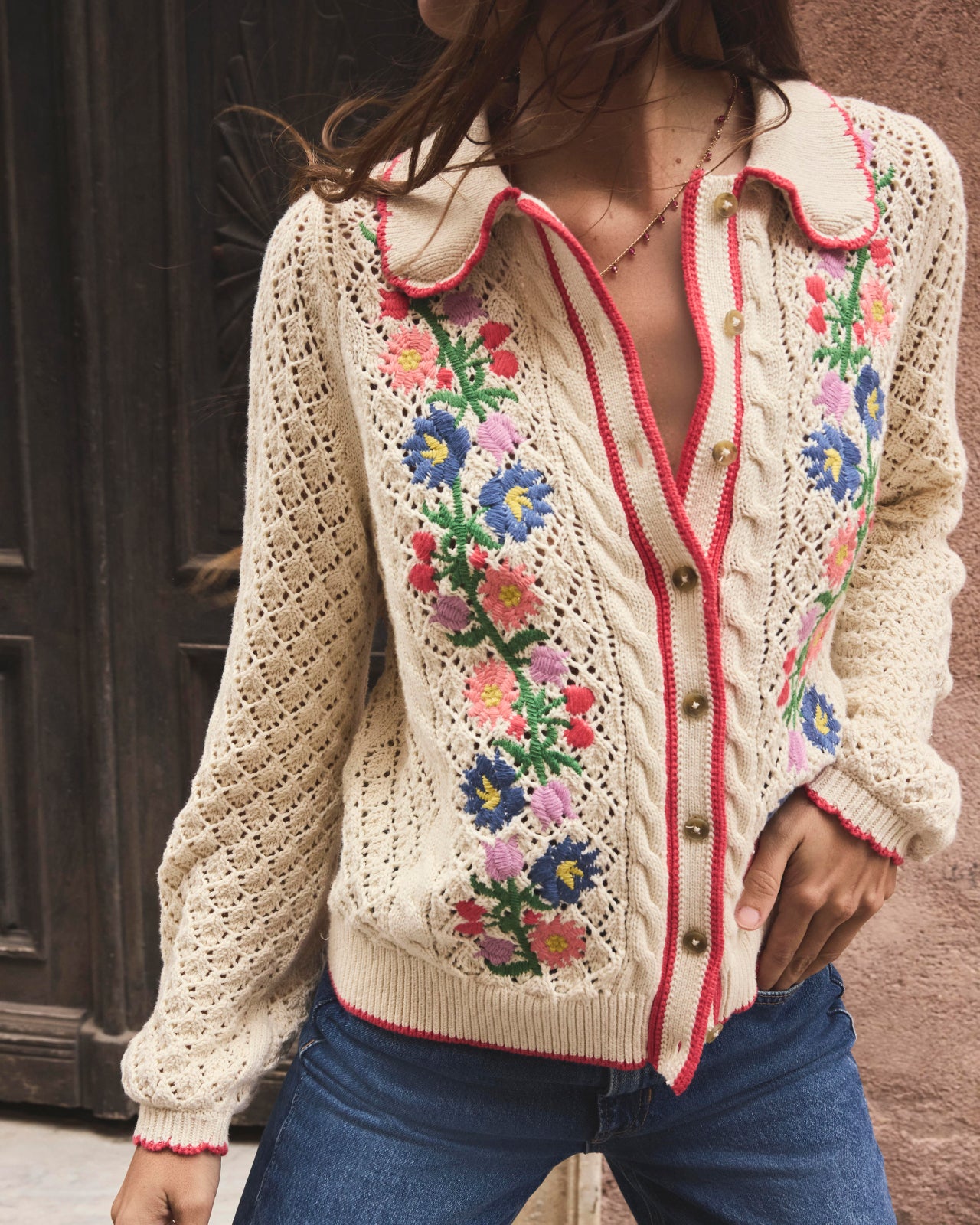 Woman in cream cardigan embroidered with flowers. Image link to women's sweaters.